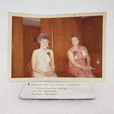[Photo] Polly Holden and Peggy Mundo Seated, 'Hospitality Girls', Region VII Meeting Calgary, Association of Desk and Derrick Clubs, Landscape, White Border, c.1972