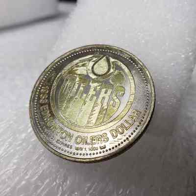 [Coin] 12 Dave Hunter/Edmonton Oilers, Hockey Dollars, 1983 - Identifier, 'Tails' Side Angled: Side angled view of 'Tails' face, showing the pattern of adhesive residue and fingerprint placement.