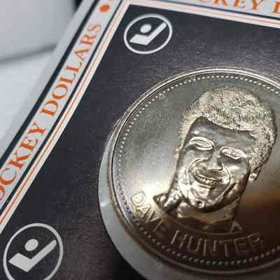 [Coin] 12 Dave Hunter/Edmonton Oilers, Hockey Dollars, 1983, In Packaging - 'Heads' Close-Up, Dents: Angled close-up view of the 'heads' face, showing the light points of denting to the left of the image of Dave Hunter.  For identification.