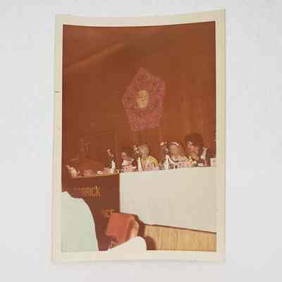 [Photo] Four Ladies Seated at Panel Table with Pengonal Wreath on Wall, Region VII Meeting Calgary, Association of Desk and Derrick Clubs, Portrait, White Border, c.1972