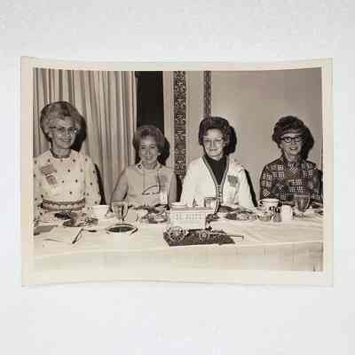[Photo] Four Ladies Seated at Table with Dr. Fudd's Wagon Centrepiece, Large, BW, Landscape, White Border, c.1972