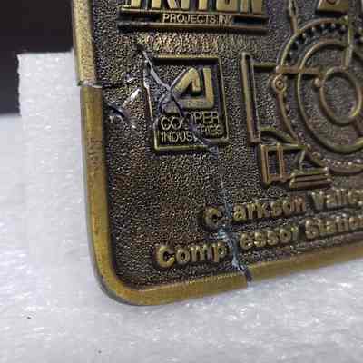 [Belt Buckle] Triton Project Inc./Nova/Cooper Industries, Clarkson Valley Compressor Station, 1991, Antique Bronze - Front, Together Close-Up: Angled close-up of broken section when pieced together, front.