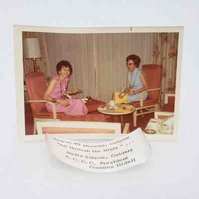 [Photo] Nadia Korpus and Frances Hidell Seated in Armchairs, Region VII Meeting Calgary, Association of Desk and Derrick Clubs, w/ Label, White Border, c.1972