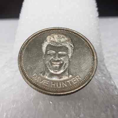 [Coin] 12 Dave Hunter/Edmonton Oilers, Hockey Dollars, 1983 - Identifier, 'Heads' Bottom Angled: View of 'Heads' face, taken from the bottom angled up. Shows denting on the rin to the mid-left; single dent to left of image of Dave Hunter; fingerprint placement.