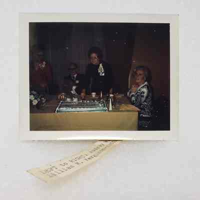 [Photo] Four Figures Around a Cake Cutting at Table, Association of Desk and Derrick Clubs, Instant Film, with Subject List Label, c.1972