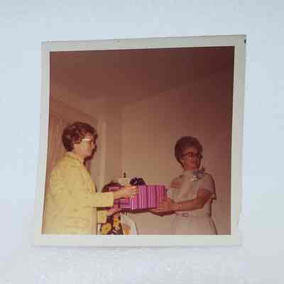 [Photo] Two Ladies with a Pink an Blue Wrapped Gift, Association of Desk and Derrick Clubs, Square, White Border, c.1972