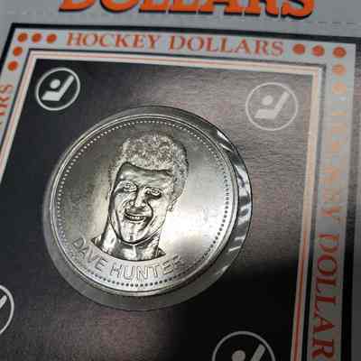 [Coin] 12 Dave Hunter/Edmonton Oilers, Hockey Dollars, 1983, In Packaging - Identifier, 'Heads' Side Angled: Angled side view of 'heads', showing the three radial scratches to the right of Dave Hunter's face (in light beam).