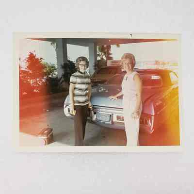 [Photo] Two Women in Front of Blue Car, Light Leaks on Sides, c.1971