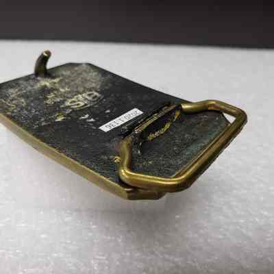 [Belt Buckle] Alberta Perforators Inc., Bronze - Hinge, Resting: Angled view of hinge, in resting position.