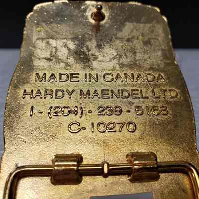 [Belt Buckle] Cage Transport Ltd., Gold Black - Maker's Mark: Close-up view of the maker's mark on the back.