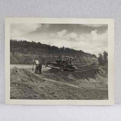 [Photo] Two Figures with Shovel and Bulldozer on River Bank, Large, BW