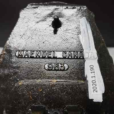 [Belt Buckle] Bert Baxter Transport, Gold Black Antique-Bronze - Maker's Mark: Close-up of the maker's mark on the back.