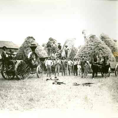 Men surrounding a steam powered thresher