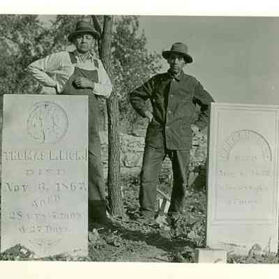 Two men behind two headstones