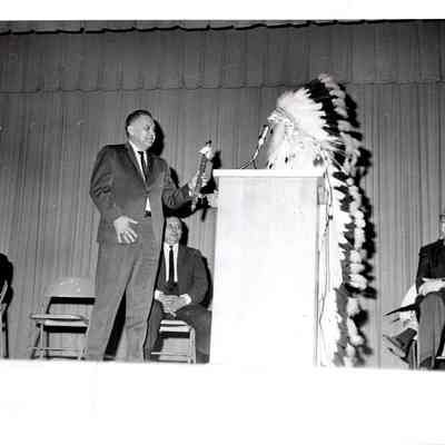Robert Bennett presenting flute to man in headdress