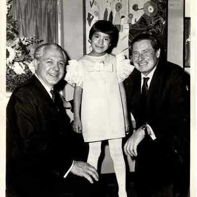 Two men in suits with young girl in dress