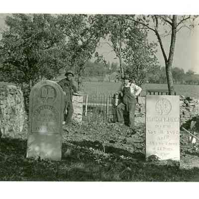 Two men behind the headstones of Patience Seketter and Thomas D. Dick