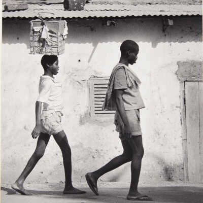 Untitled (two women walking, one with box balanced on head)