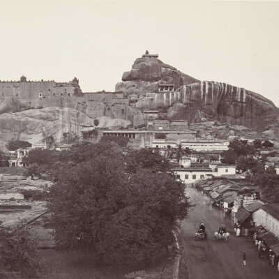 Untitled ("2005" - Street scene with cars and rows of buildings below monumental stones/village - India?)