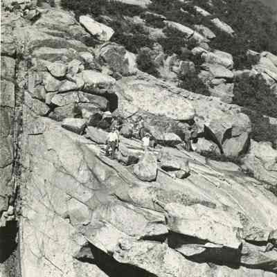 Individuals atop Cannon Cliff