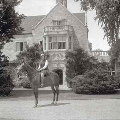 Coe_Caroline_013: Caroline Coe on horseback in front of Coe Hall at Planting Fields