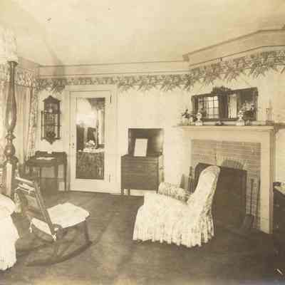 Byrne_030: Interior of bedroom with chair in front of brick fireplace, photographed by August Patzig