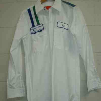 White shirt with two navy vertical stripes, Alaska Airlines 727 "fly with a happy face" patch on right shoulder. Left chest patch name "Ed".