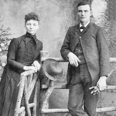 young couple, woman and man posed against a fence