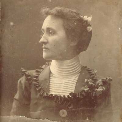 The woman's high collared blouse and hairstyle suggest sometime between 1890 and 1918.