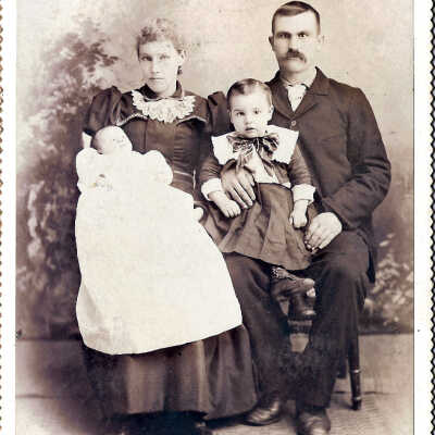 family portrait of woman holding infant and man holding toddler