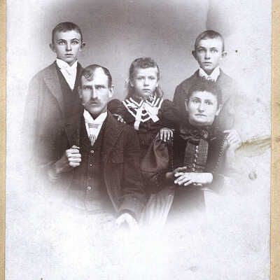 family of seated man & woman with children (2 boys and a girl)