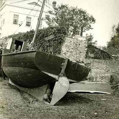 Boats washed up in front of walls and house