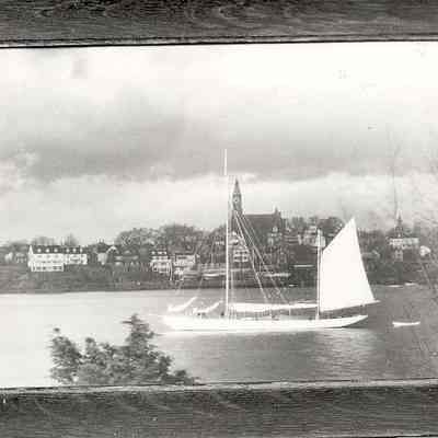 Picture of sailing boat going down river in front of town