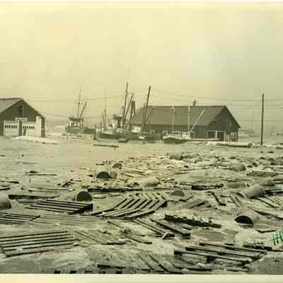Town dock with fishing boats, buildings and debris