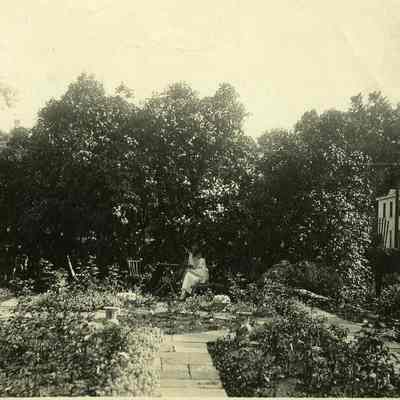 Woman sitting under tree in garden at "The Hill"