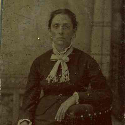 Unknown woman in chair with dark hair and earrings