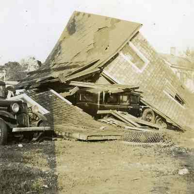 Wrecked automobiles under collapsed house