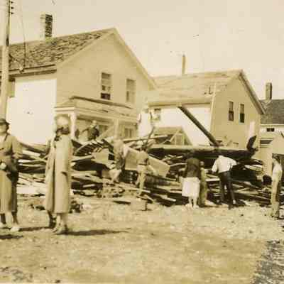 People walking by damaged houses