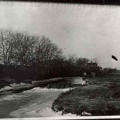 Unidentified scene with river/flooded stream with house in background