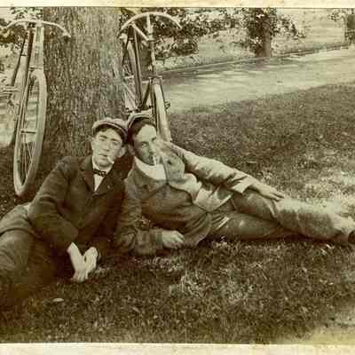 Unknown men on ground against tree with bicycles