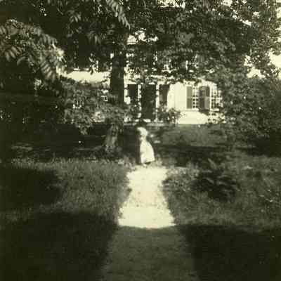 Woman under tree, house in background at "The Hill"