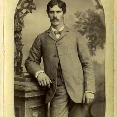 Unknown young, dark-haired man leaning against column
