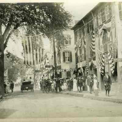 Car driving on Water Street, Stonington CT with flags on buildings
