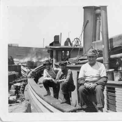 Three men sitting on deck of vessel