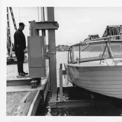 Marine Travelift holding vessel over water next to Michigan Street Bridge