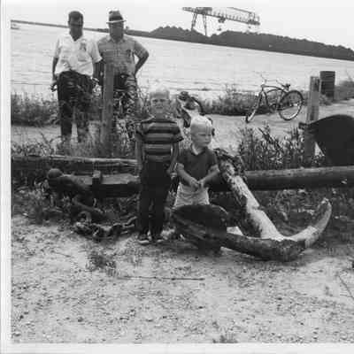 Two adult and two kids next to two crossed anchors