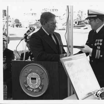 Omer Mickelson being presented framed drawing of USCGC Mobile Bay 1979