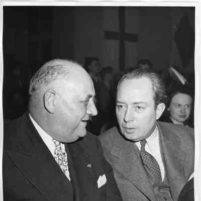Two unidentified men sitting and talking at ship launching