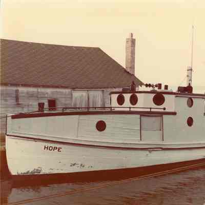 Fishing tug Hope docked in front of building 1980