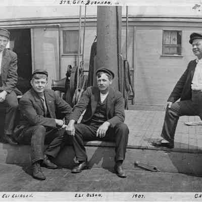 Four men posing in front of Str. Geo. Burnham